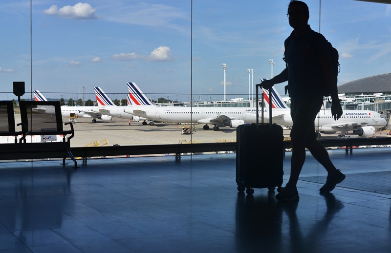 A silhouette of a passenger with a suitcase on the background of Air France planes at Charles de Gaulle Airport